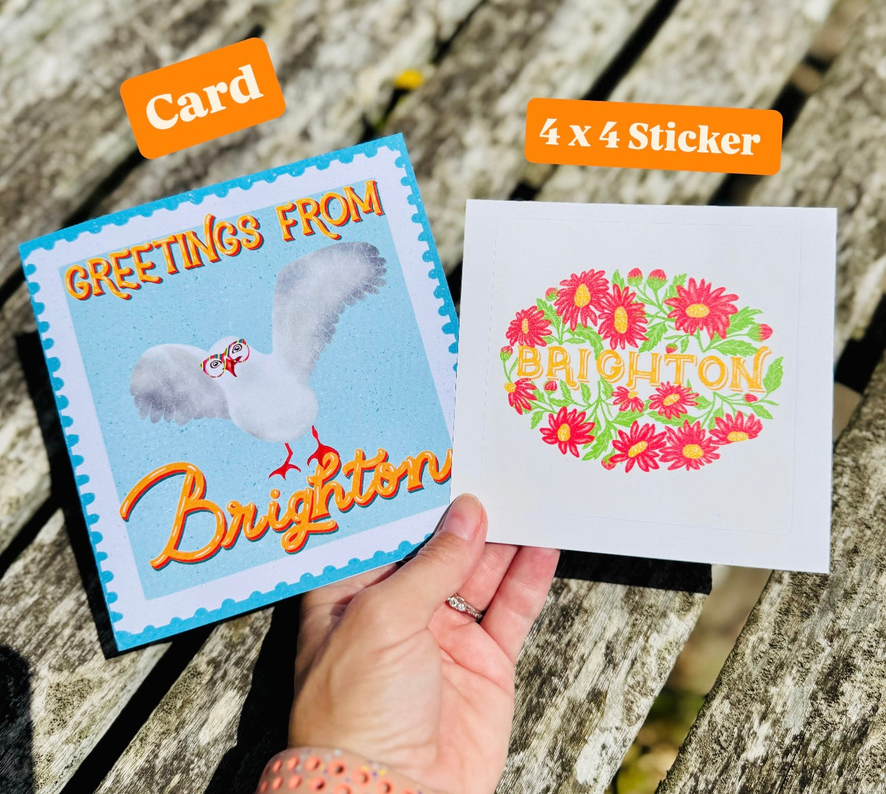 Card and 4x4 sticker with 'Greetings from Brighton' text and floral design on a wooden surface.