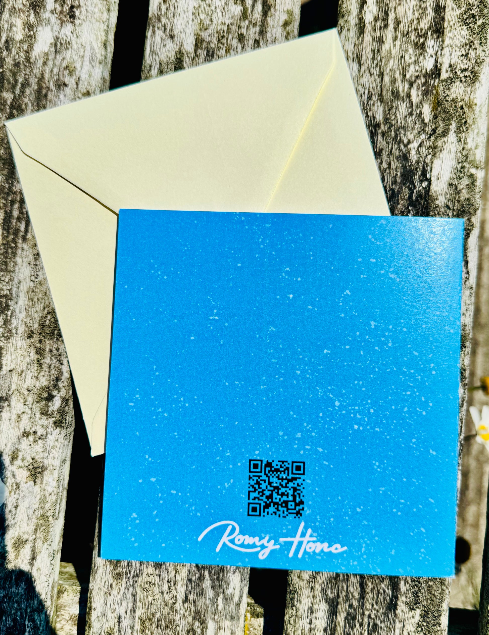 Blue card with QR code and 'Romy Home' text on a wooden surface