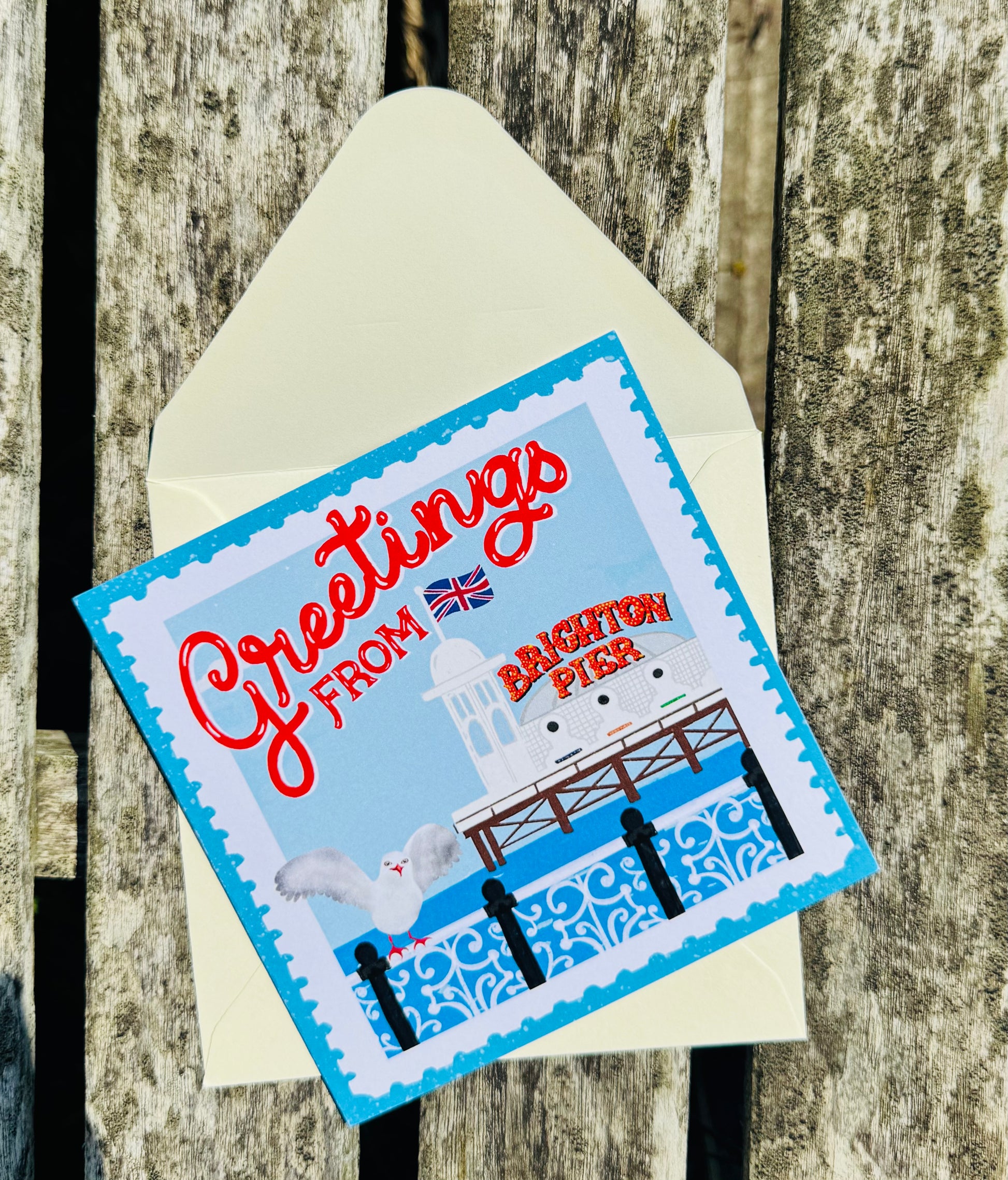 Greeting card with 'Greetings from Brighton Pier' text and a seagull design on a wooden background.