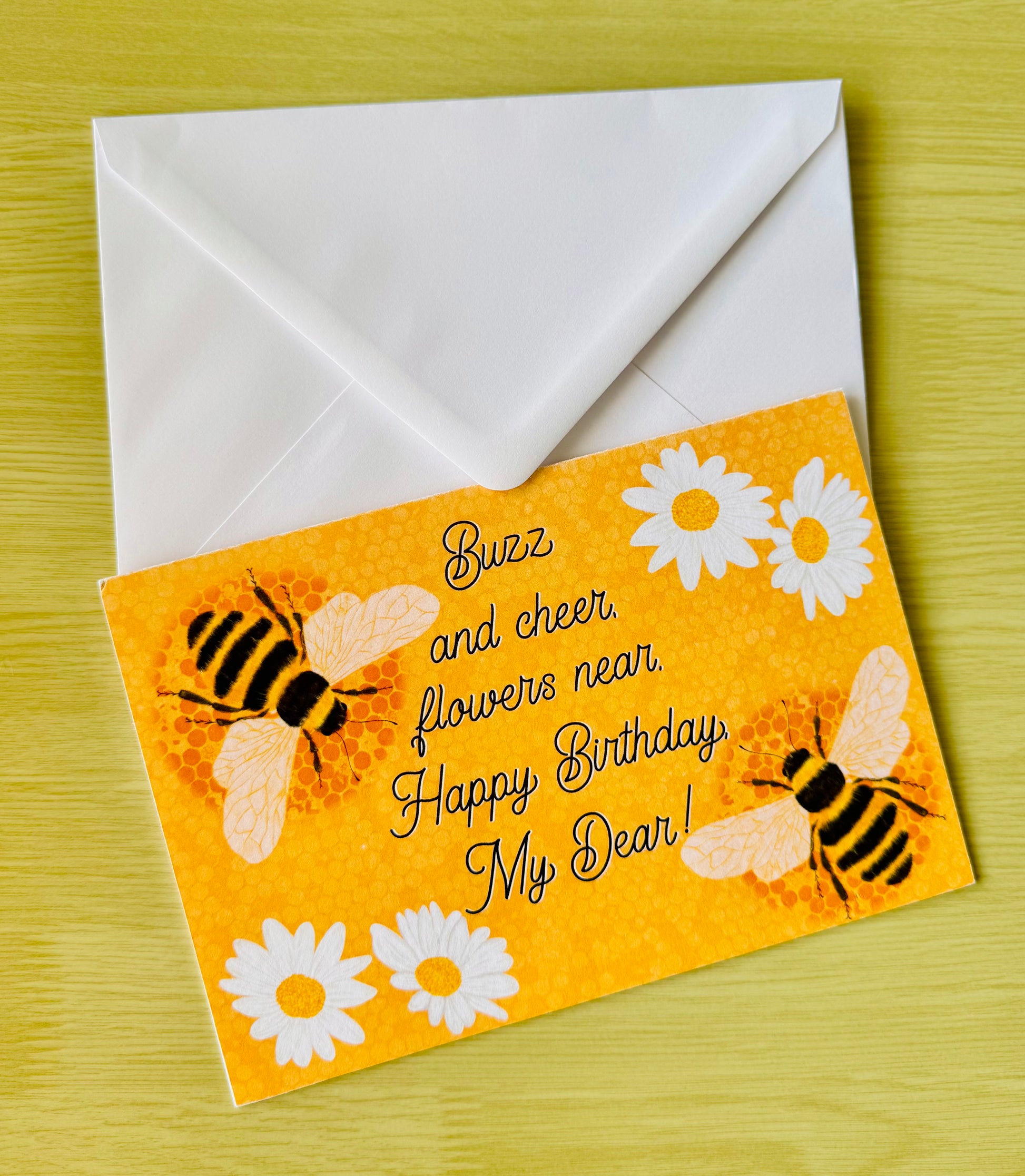 Birthday card with bees and flowers on an orange background, featuring a white envelope.