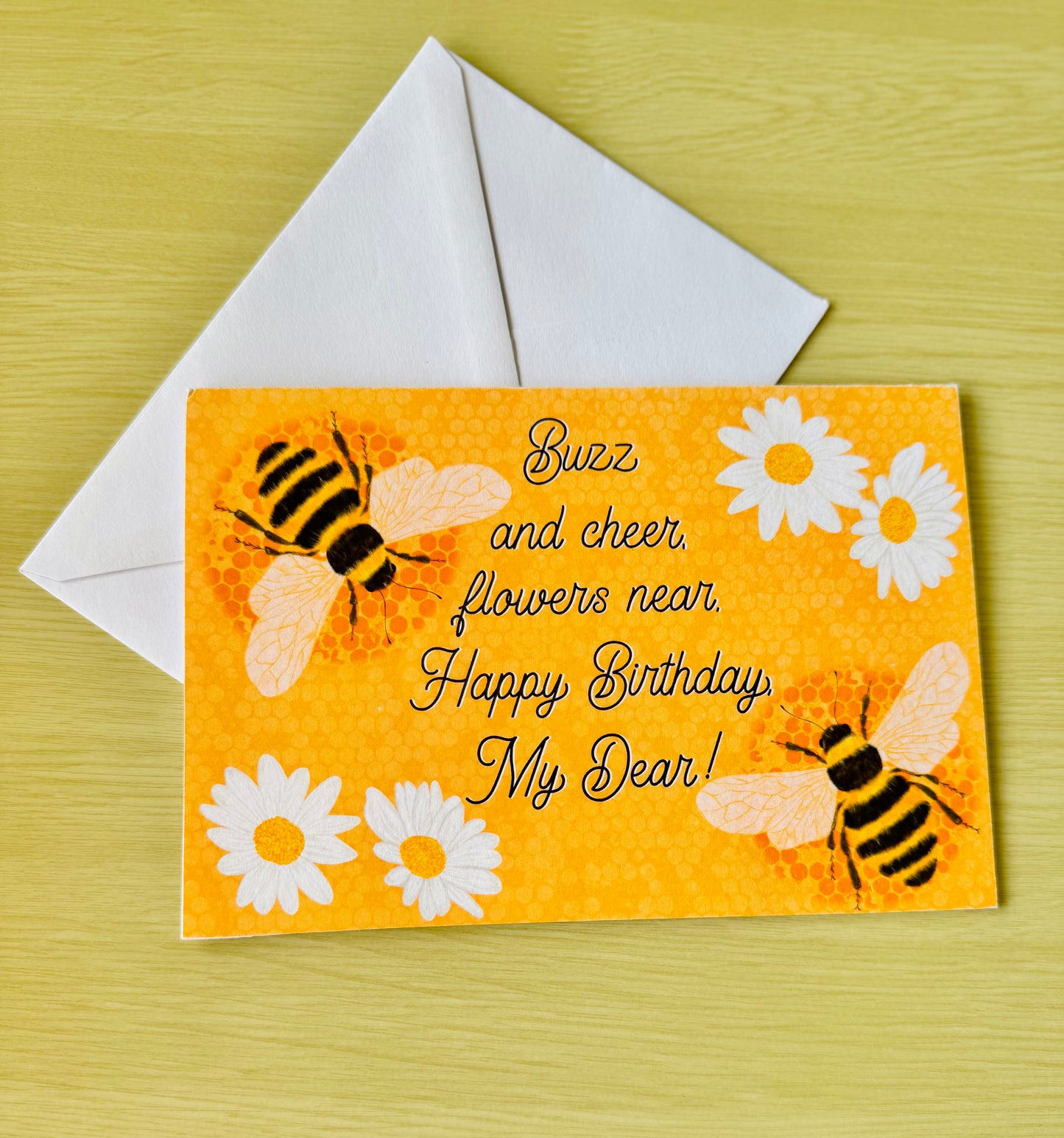 Birthday card with bees and flowers on an orange background, featuring a white envelope.