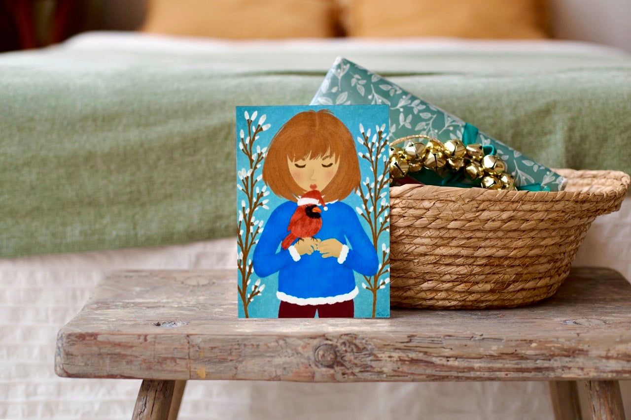 Small painting of a girl holding a bird on a wooden table with a textured surface.