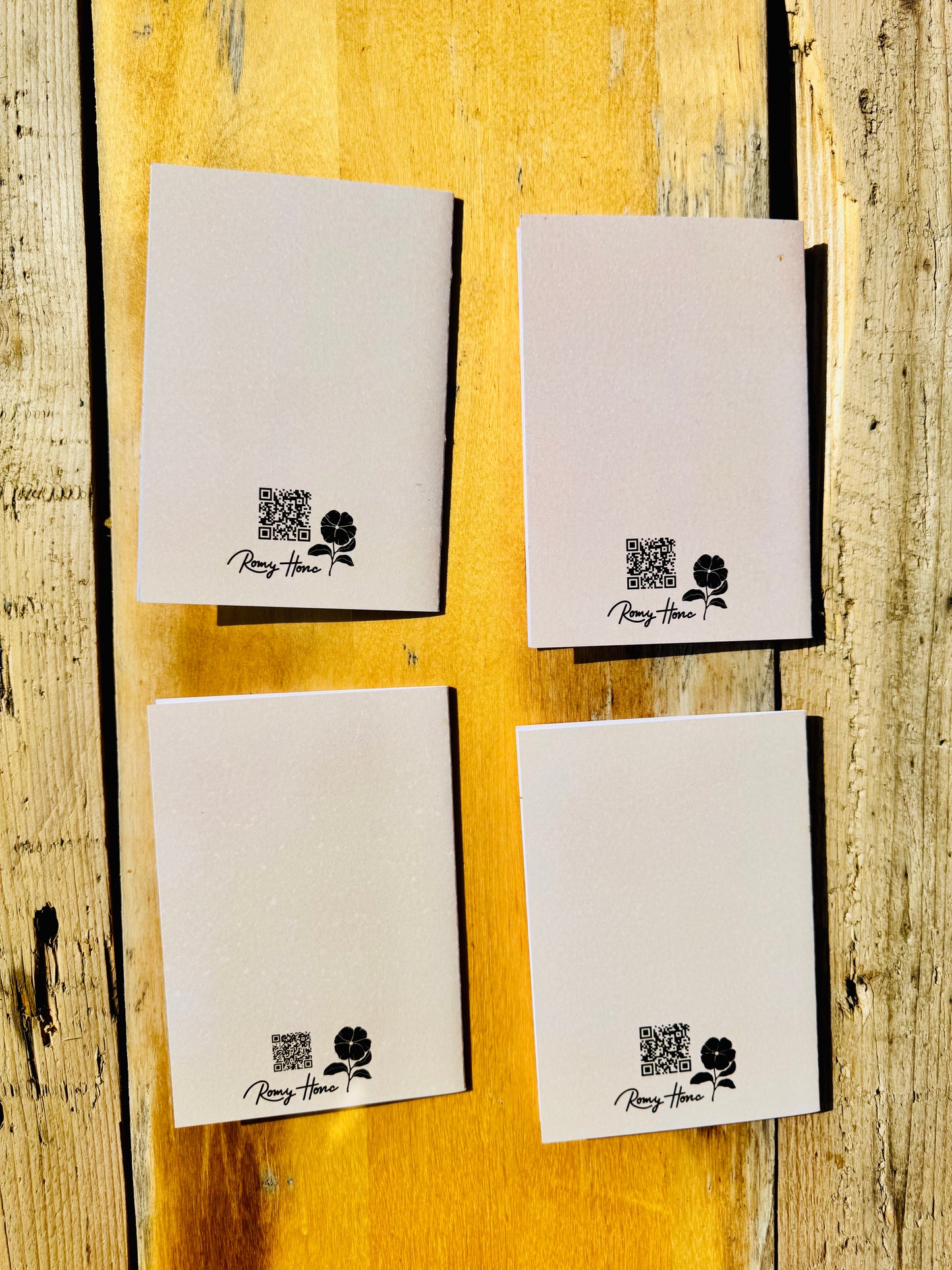 Four white rectangular cards or envelopes arranged in a 2x2 grid on a rustic yellow wooden surface. Each card has a small black QR code, a rose illustration, and the text 'Peach House' printed near the bottom.